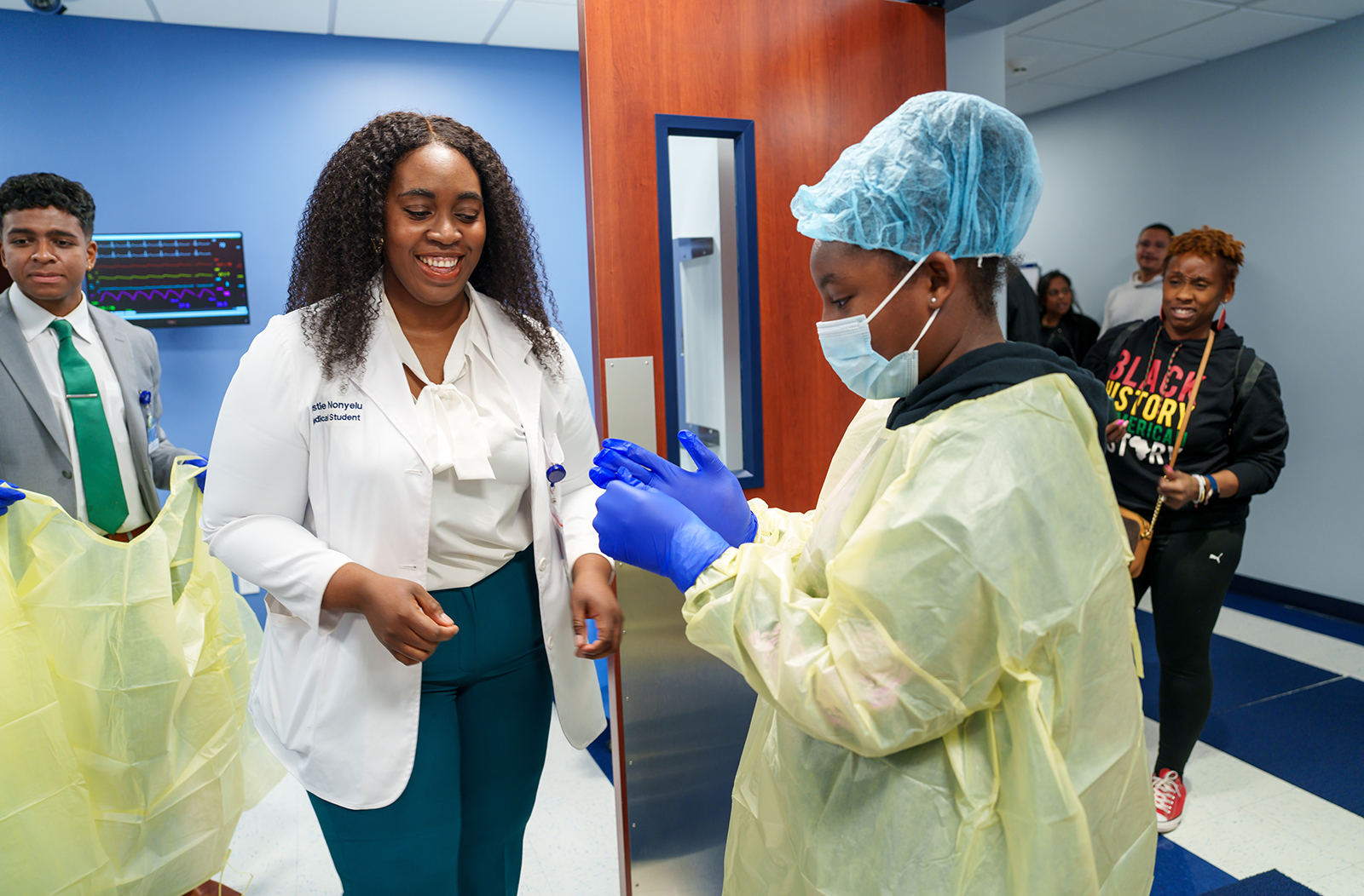 Third-year medical student Kristie Nonyelu doing a "mock" surgery scrub-in with an attendee of the Black Men in White Coats event